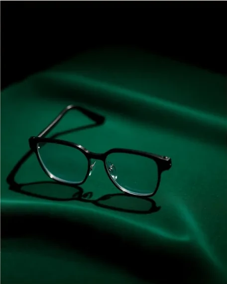 Monture rectangulaire sombre sur une soie vert profond